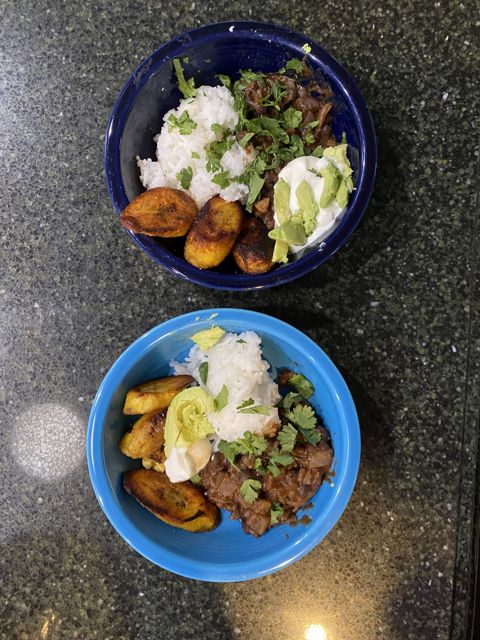 Two bowls of rice with plantains, avocado, and cilantro