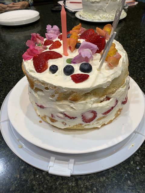 A layered strawberry cream cake with candles