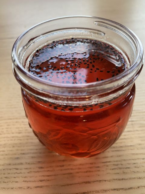 A glass jar of deep red drink, seen from above
